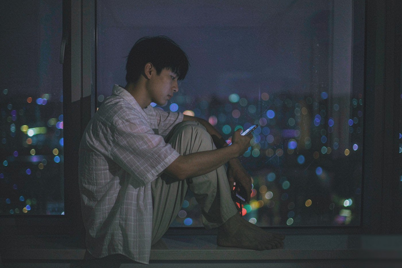 深夜独自坐在窗边看着城市夜景的人